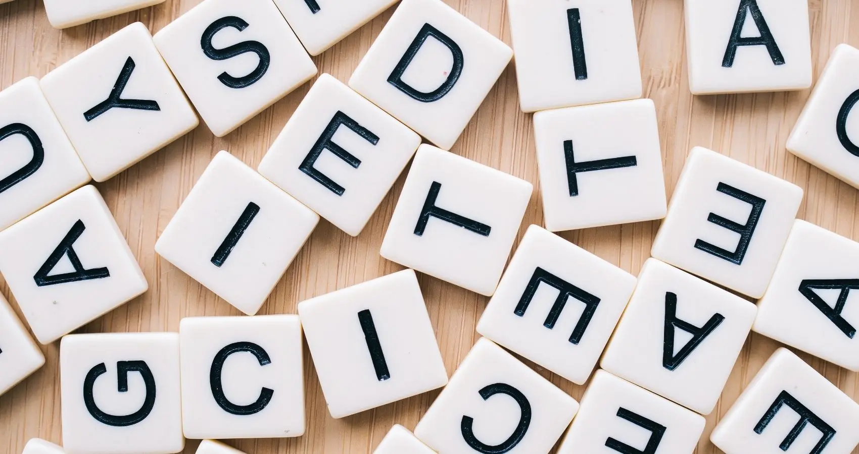 Lettres éparpillées sur une surface en bois, symbolisant les mots et le choix des paroles avant de les exprimer.